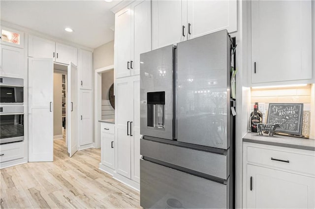 kitchen featuring light countertops, white cabinets, light wood finished floors, stainless steel appliances, and recessed lighting