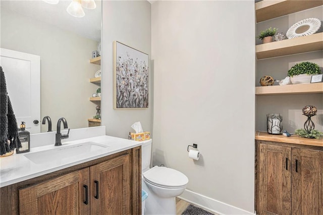 bathroom with toilet, baseboards, and vanity