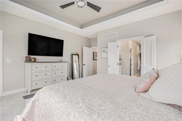 bedroom featuring visible vents, carpet floors, baseboards, ceiling fan, and a tray ceiling