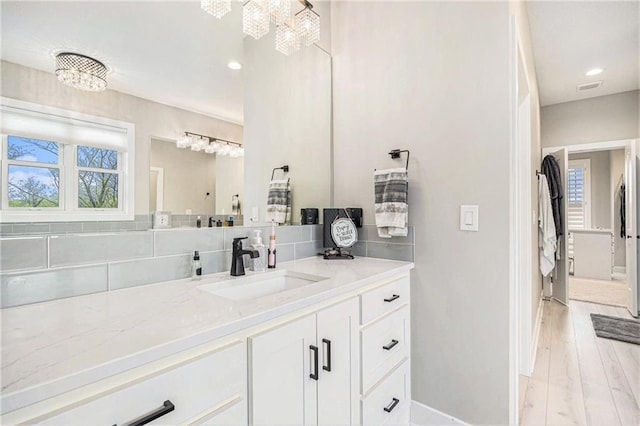 bathroom with vanity, recessed lighting, baseboards, and backsplash