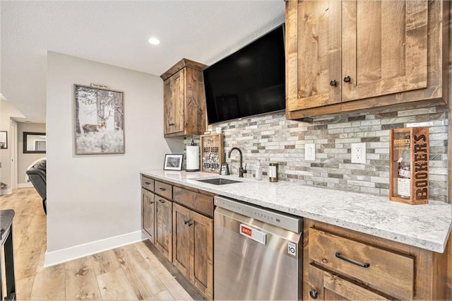 kitchen featuring a sink, light wood-style floors, dishwasher, baseboards, and decorative backsplash