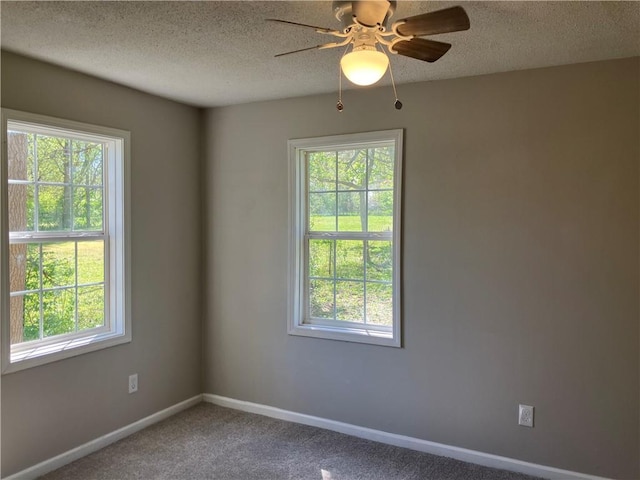 carpeted spare room featuring healthy amount of natural light, ceiling fan, a textured ceiling, and baseboards