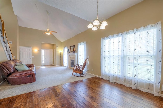 living room with hardwood / wood-style floors, baseboards, a wealth of natural light, and ceiling fan with notable chandelier