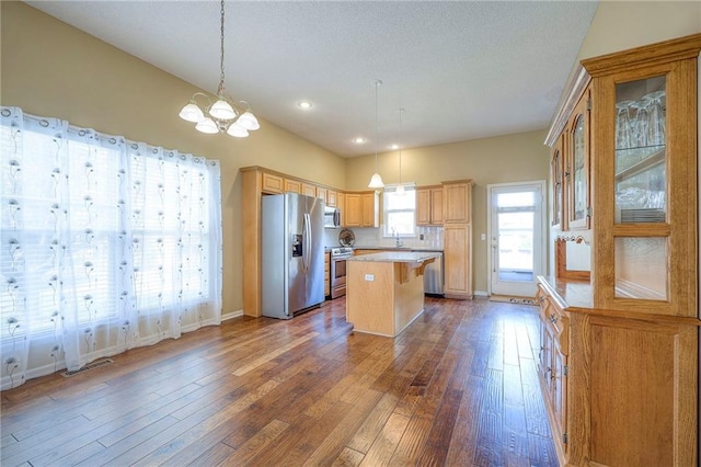 kitchen with a sink, a chandelier, stainless steel appliances, light countertops, and dark wood finished floors
