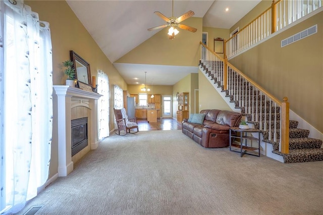living area featuring stairs, ceiling fan, carpet flooring, visible vents, and high vaulted ceiling