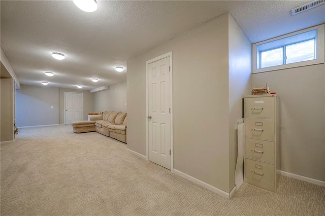 interior space with a textured ceiling, carpet flooring, baseboards, and visible vents