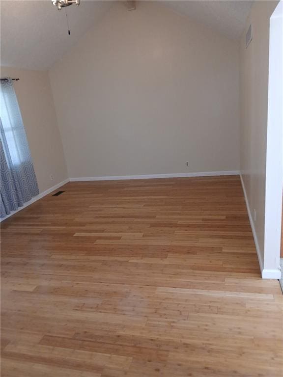 unfurnished room with vaulted ceiling, baseboards, and light wood finished floors