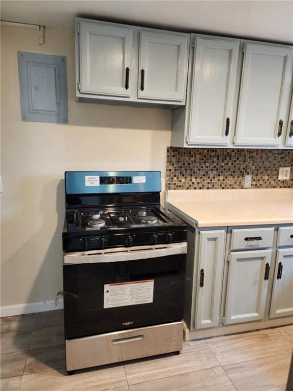 kitchen with stainless steel range with gas stovetop, electric panel, light countertops, and baseboards