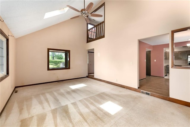 32832 195th St, Leavenworth, KS 66048 - unfurnished living room with light carpet, ceiling fan, high vaulted ceiling, baseboards, and a skylight