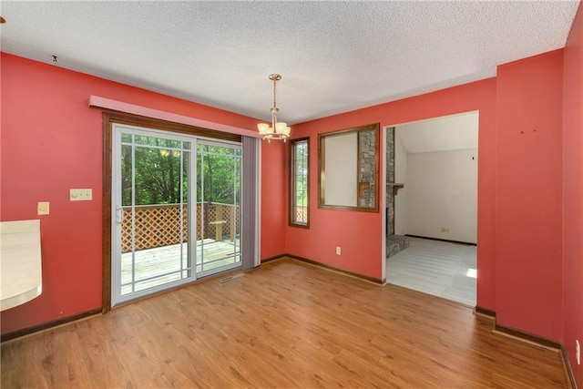 32832 195th St, Leavenworth, KS 66048 - unfurnished dining area with wood finished floors, a chandelier, a textured ceiling, and baseboards