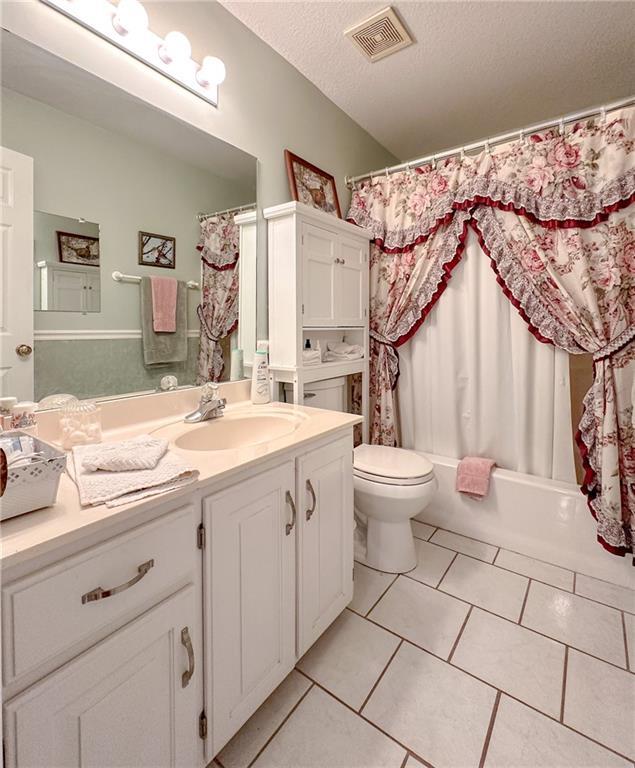 15404 NE 181st St, Holt, MO 64048 - bathroom with vanity, toilet, tile patterned flooring, shower / bathtub combination with curtain, and a textured ceiling