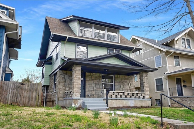 3009 Campbell St, Kansas City, MO 64109 - view of front of house featuring a shingled roof, covered porch, stone siding, and fence