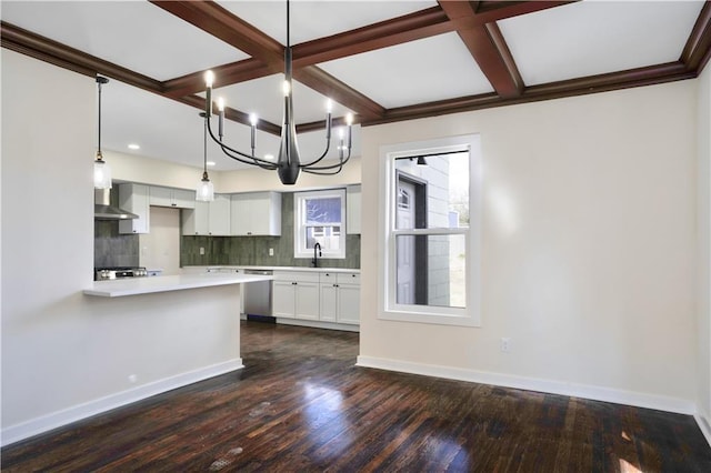 3009 Campbell St, Kansas City, MO 64109 - kitchen with wall chimney range hood, a chandelier, light countertops, white cabinets, and coffered ceiling
