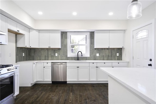 3009 Campbell St, Kansas City, MO 64109 - kitchen with white cabinets, a sink, dark wood-style flooring, light countertops, and stainless steel appliances