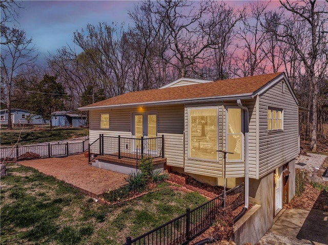 view of front of house with an attached garage, a patio, french doors, and fence