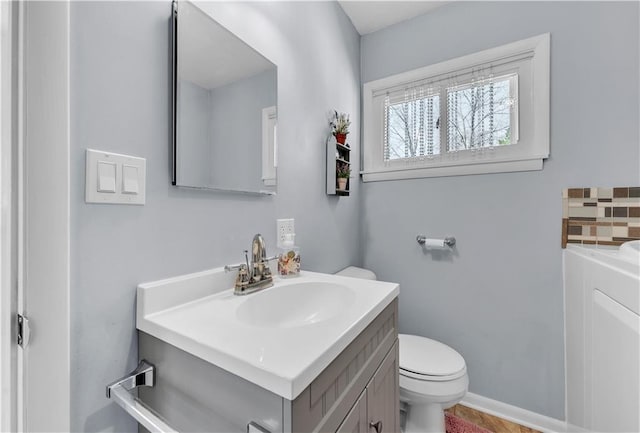 bathroom featuring tasteful backsplash, toilet, and vanity
