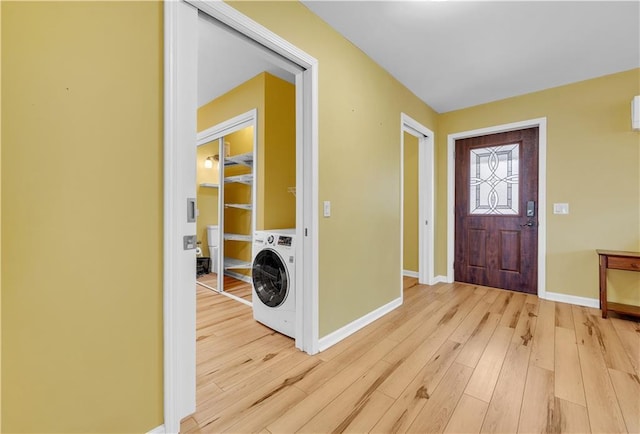 entryway with light wood-style flooring, baseboards, and washer / dryer