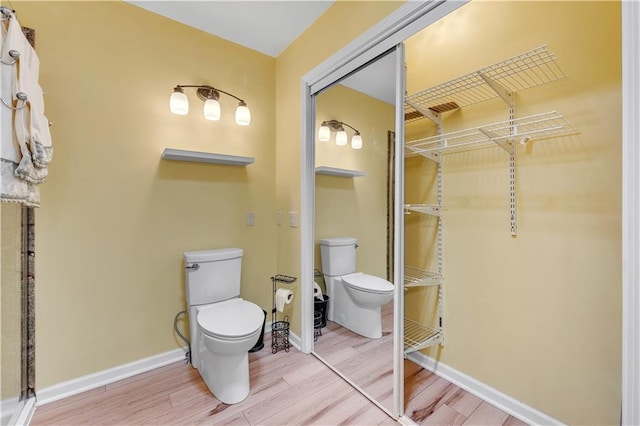 bathroom featuring toilet, wood finished floors, and baseboards