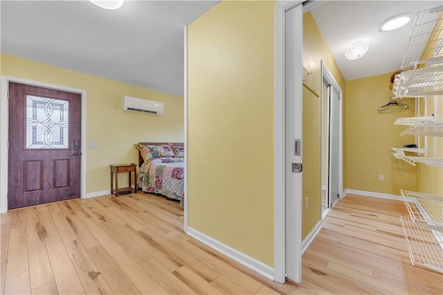 entrance foyer with light wood finished floors, baseboards, and an AC wall unit