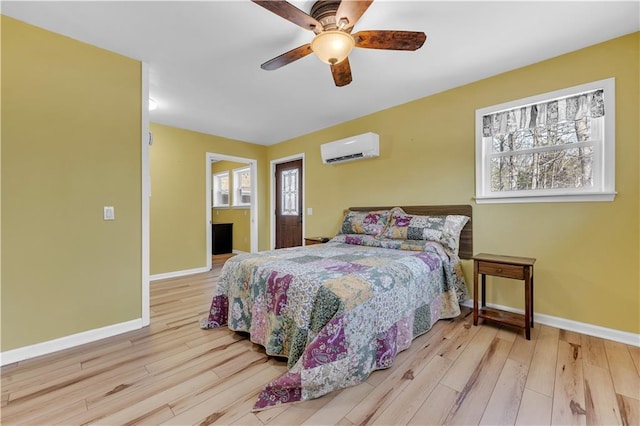 bedroom with hardwood / wood-style floors, a wall unit AC, ceiling fan, and baseboards