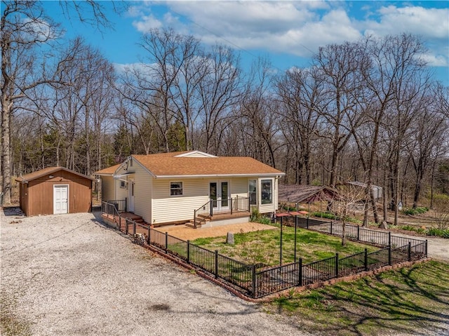 view of front of home with a front yard, driveway, a storage shed, an outbuilding, and fence private yard