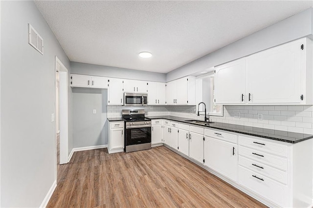 710 N Redwood Dr, Independence, MO 64056 - kitchen with dark countertops, visible vents, a sink, and appliances with stainless steel finishes