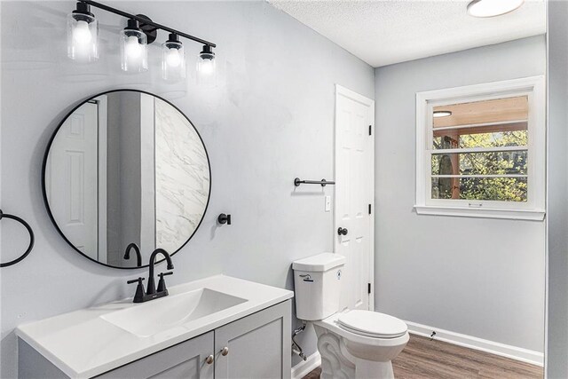 710 N Redwood Dr, Independence, MO 64056 - bathroom featuring wood finished floors, a textured ceiling, vanity, baseboards, and toilet