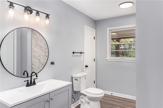 710 N Redwood Dr, Independence, MO 64056 - bathroom featuring toilet, vanity, wood finished floors, and baseboards