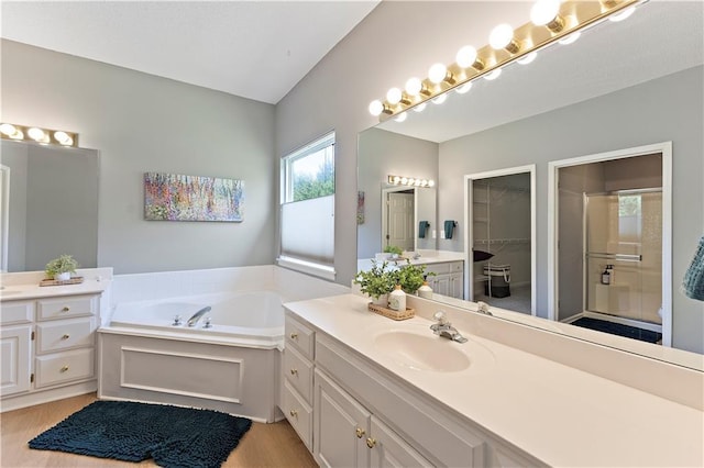 bathroom featuring a walk in closet, a shower stall, vanity, wood finished floors, and a garden tub