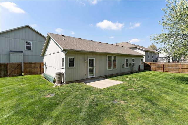 rear view of house with a yard, roof with shingles, a fenced backyard, and a patio area