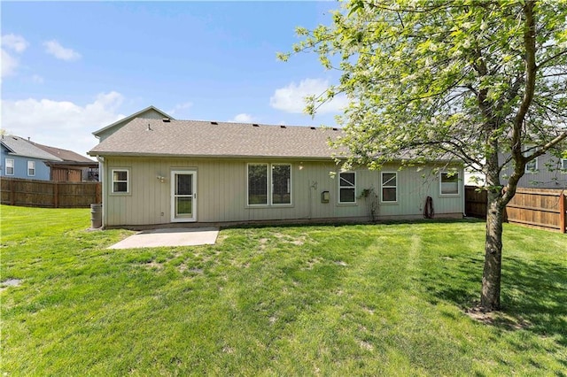 back of property with a fenced backyard, a patio, a lawn, and roof with shingles