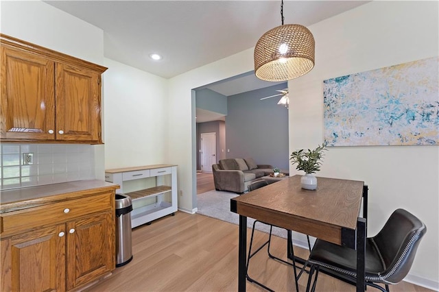 dining area with ceiling fan, light wood finished floors, and baseboards