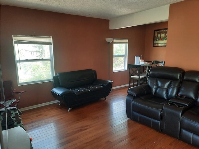 living room with wood-type flooring, a textured ceiling, and baseboards