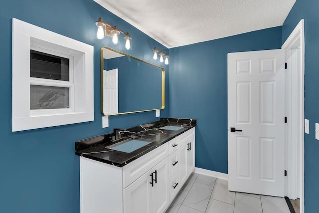 bathroom with baseboards, a sink, a textured ceiling, double vanity, and marble finish floor