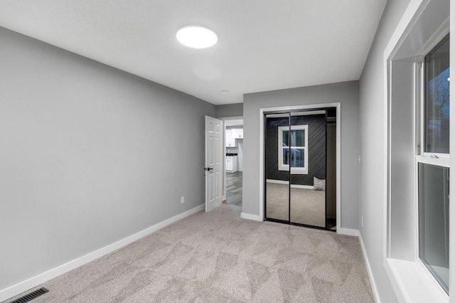 unfurnished bedroom with a closet, carpet, visible vents, and baseboards