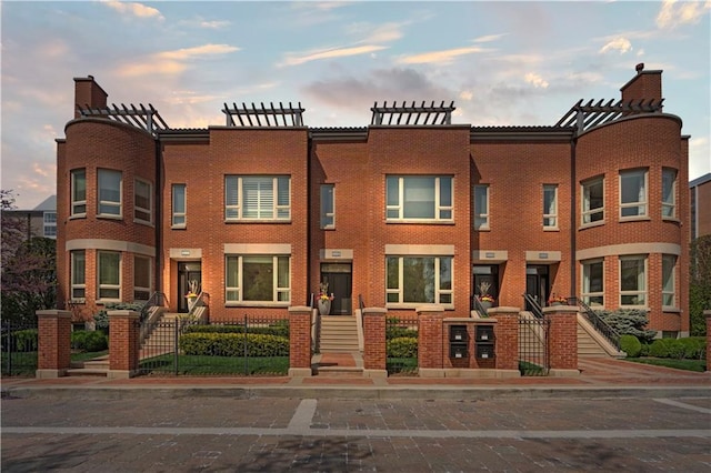 4924 Central St, Kansas City, MO 64112 - townhome / multi-family property with fence, a chimney, and brick siding