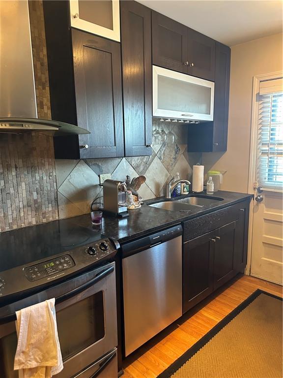 4209 Clark Ave Unit 4209-4, Kansas City, MO 64111 - kitchen with stainless steel appliances, tasteful backsplash, wall chimney exhaust hood, and a sink