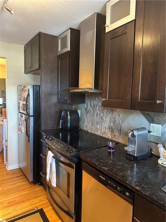 4209 Clark Ave Unit 4209-4, Kansas City, MO 64111 - kitchen with light wood-type flooring, appliances with stainless steel finishes, wall chimney exhaust hood, and dark brown cabinets