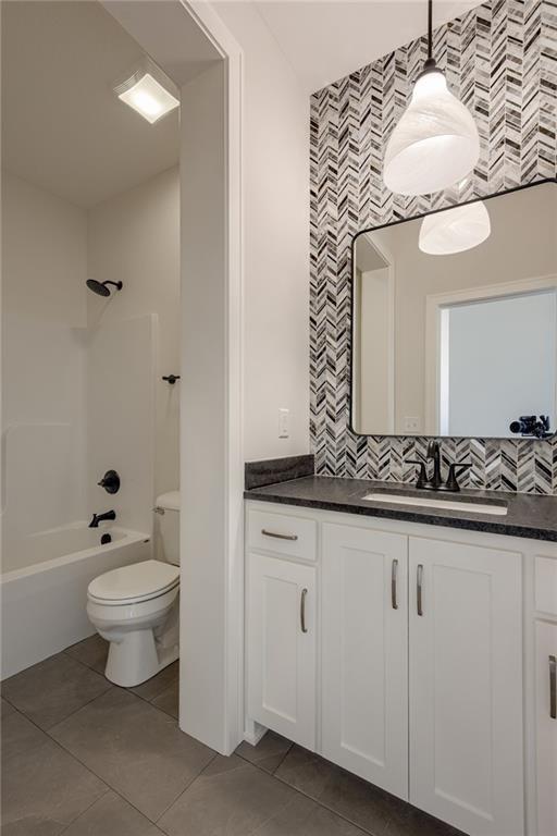 8216 NW 89th Ter, Kansas City, MO 64153 - bathroom featuring toilet, vanity, tile patterned flooring, and washtub / shower combination