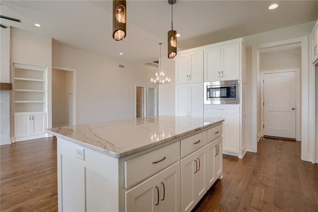 8216 NW 89th Ter, Kansas City, MO 64153 - kitchen featuring white cabinets, stainless steel microwave, a chandelier, and wood finished floors