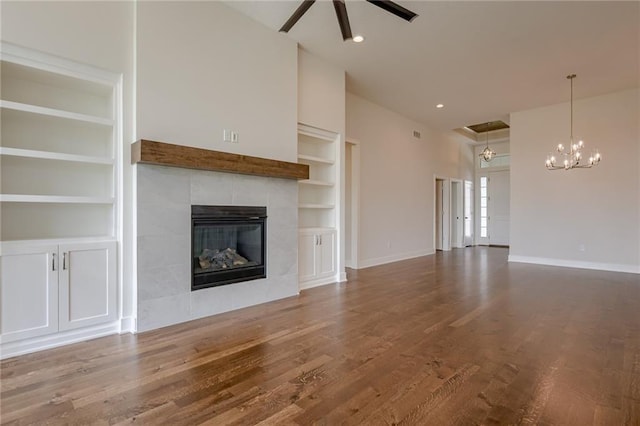 8216 NW 89th Ter, Kansas City, MO 64153 - unfurnished living room with built in features, baseboards, a tiled fireplace, wood finished floors, and ceiling fan with notable chandelier