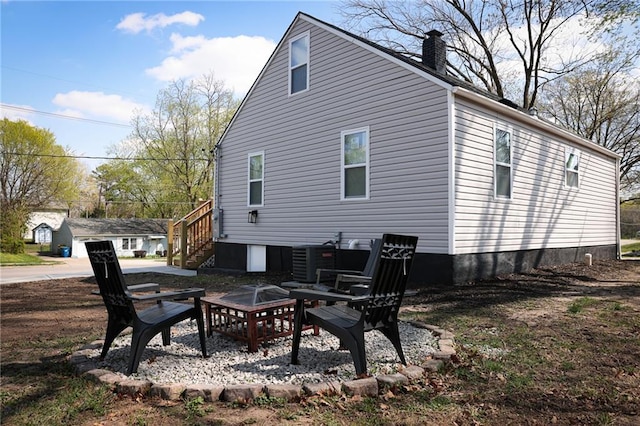 5606 N Indiana Ave, Kansas City, MO 64119 - back of property with a fire pit, a chimney, and cooling unit