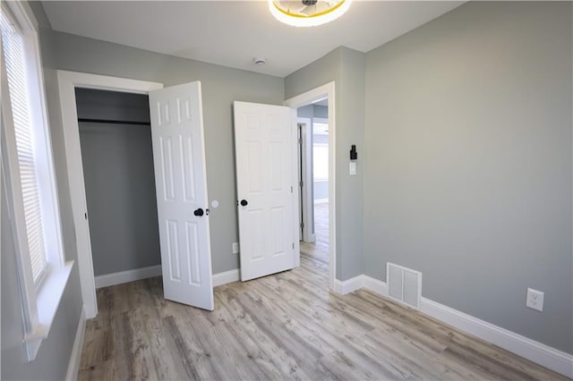 5606 N Indiana Ave, Kansas City, MO 64119 - unfurnished bedroom with visible vents, multiple windows, and light wood-style floors