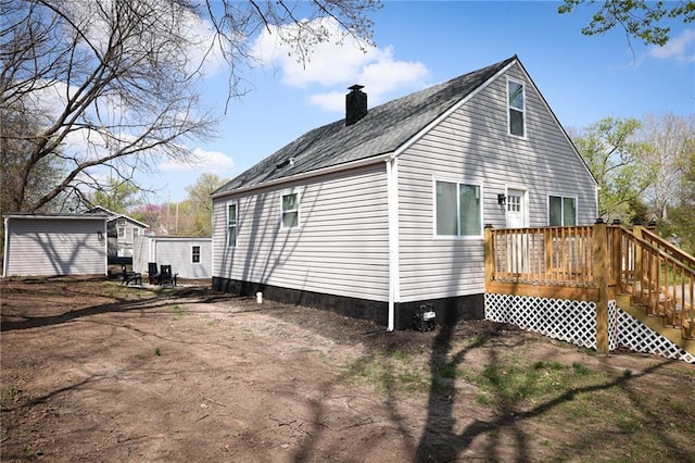 5606 N Indiana Ave, Kansas City, MO 64119 - view of side of home featuring a chimney, a wooden deck, stairway, an outdoor structure, and a shingled roof