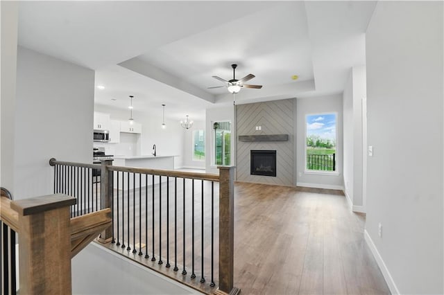 2433 NW Sunnyvale Ct, Blue Springs, MO 64015 - living area featuring a raised ceiling, ceiling fan, baseboards, light wood-type flooring, and a large fireplace