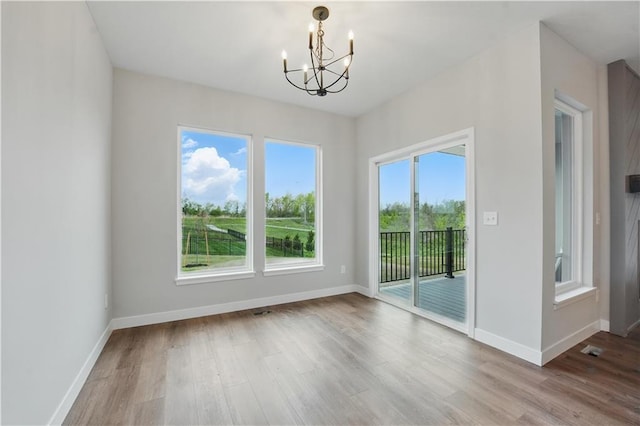 2433 NW Sunnyvale Ct, Blue Springs, MO 64015 - unfurnished dining area with a chandelier, wood finished floors, and baseboards