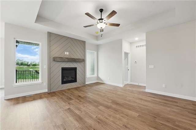 2433 NW Sunnyvale Ct, Blue Springs, MO 64015 - unfurnished living room featuring a raised ceiling, ceiling fan, wood finished floors, baseboards, and a fireplace