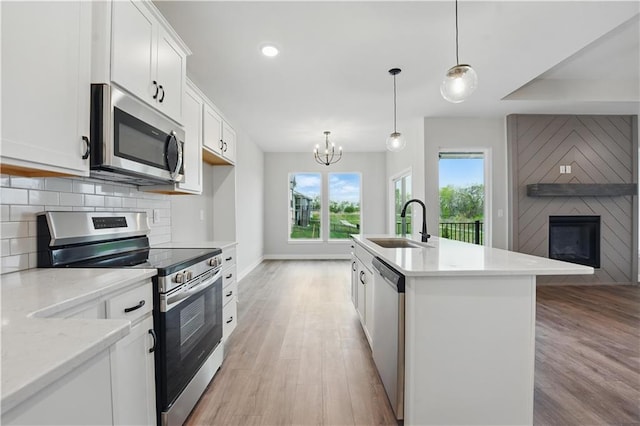 2433 NW Sunnyvale Ct, Blue Springs, MO 64015 - kitchen featuring stainless steel appliances, a sink, a fireplace, light wood-style flooring, and recessed lighting