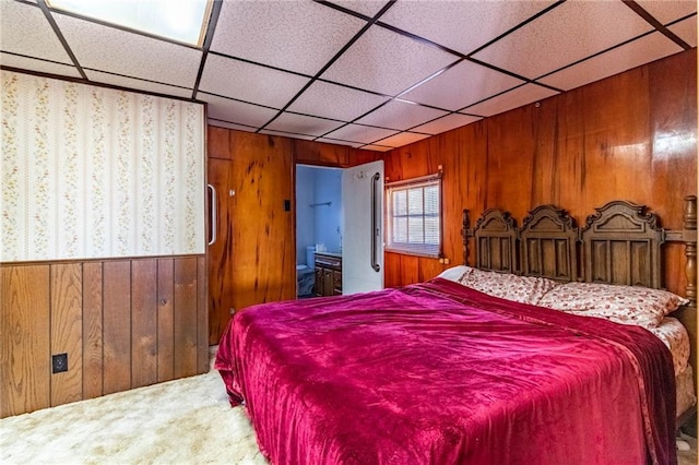 bedroom with carpet flooring, wooden walls, and a drop ceiling