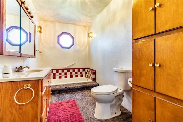 full bathroom with a bath, toilet, vanity, and a textured ceiling
